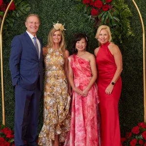 Four people standing take a photo underneath an arch