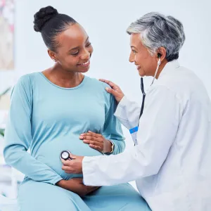 A doctor listening to the pregnant women heartbeat
