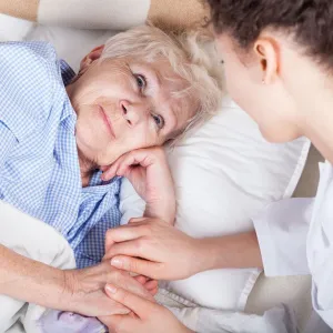 a nurse holding a patient hand and smiling