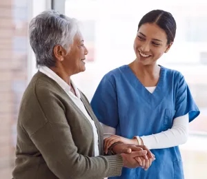 a nurse holding hands with a patient and smiling