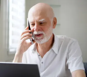 a senior calling while using his laptop