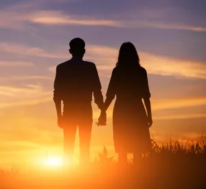 a man and women holding hands watching the sunset